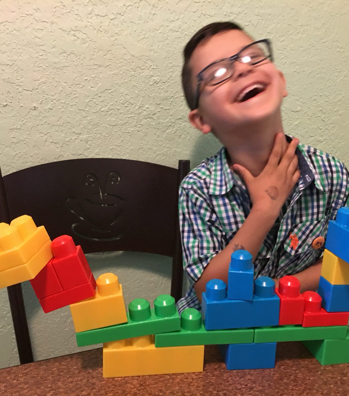 Boy with a precarious lego building laughing